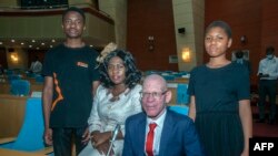 L'ancien président de l'Association des personnes atteintes d'albinisme au Malawi, Overstone Kondowe (1er plan), avec sa femme Memory (assise) et leurs enfants, Promise (à g.) et Ellen, au Parlement du Malawi, le 4 novembre 2021. 