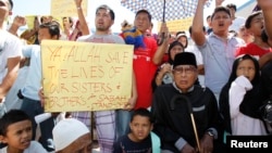 Former Sultan of Sulu Jamalul Kiram III (seated at R) with his followers display placards in front of Blue Mosque in Maharlika village, Taguig city, south of Manila, March 1, 2013