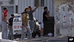 Residents of the Shiite Muslim village of Malkiya, Bahrain, southwest of Manama, watch, some with stones in hand and others photographing riot police and tanks moving in, March 20, 2011