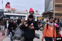Hundreds of migrants and refugees walk at the port of Piraeus upon their arrival from Lesbos, Feb. 10, 2016. The EU's migration commissioner urged member states to accelerate relocation of refugees from overstretched Greece and Italy.