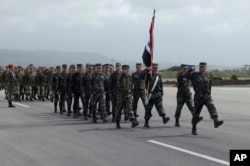 In this photo provided by the Russian Defense Ministry Press Service, Syrian troops march during a send-off ceremony for Russian troops at Hemeimeem air base in Syria, March 15, 2016.