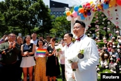Gay newlyweds walk on a giant rainbow flag at a same-sex marriage party after registering their marriage in Taipei, Taiwan, May 24, 2019.