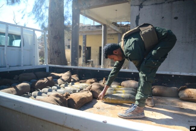 In this image provided by the U.S. Army, a Raqqah Internal Security Force member loads unexploded ordnance onto a truck for proper disposal in Raqqah, Syria, on Feb. 19, 2018.