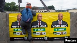 African National Congress (ANC) election posters featuring images of South Africa's President Jacob Zuma are displayed on a wall as a school boy climbs over it in Embo, May 6, 2014.