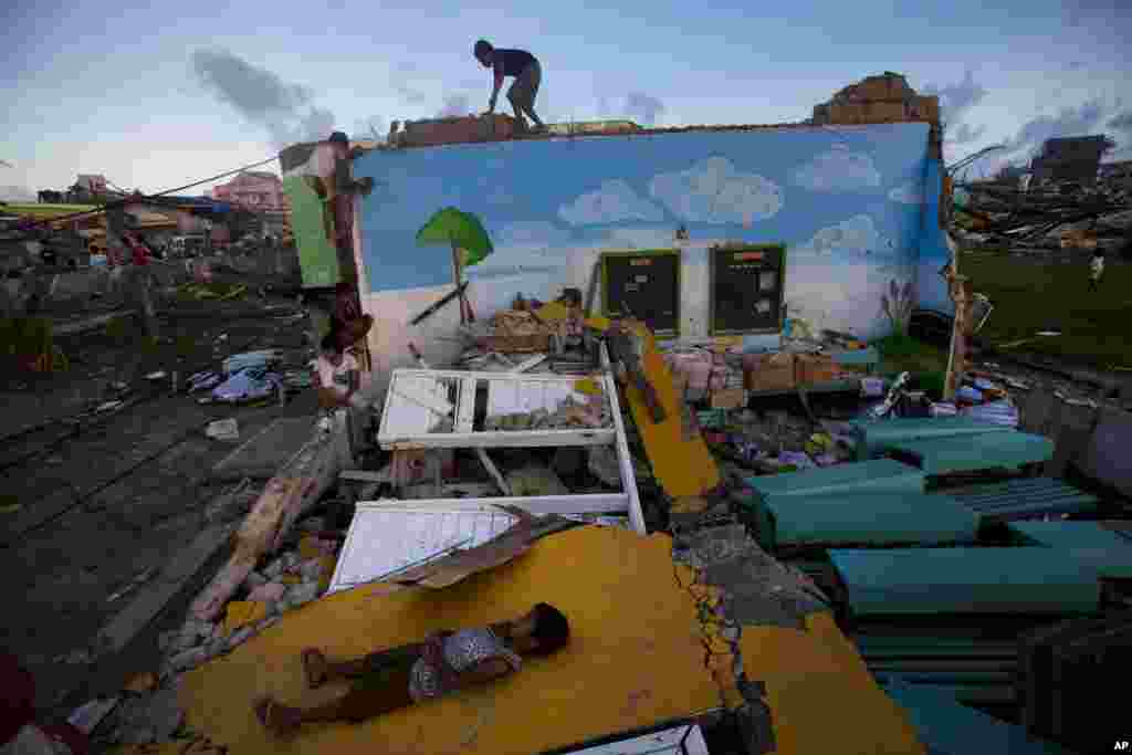 Anak-anak penyintas bermain di atas puing-puing gedung sekolah dasar mereka di Guiuan, Filipina (14/11). (AP/David Guttenfelder)