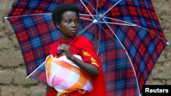 FILE - A young woman covers her baby from the hot sun in Burundi's capital, Bujumbura.