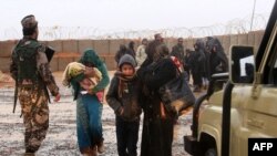 FILE - Syrian refugee patients from the Rukban camp, located close to the Tanf U.S. military base in the desert near where the borders of Syria, Jordan and Iraq converge, cross over to visit a U.N.-operated medical clinic immediately on the Jordanian side for checkups, March 1, 2017.