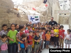 Rami Adham is surrounded by Syrian children who gather near a field school in Aleppo that has since been destroyed, Sept. 2015. (photo courtesy of Rami Adham)