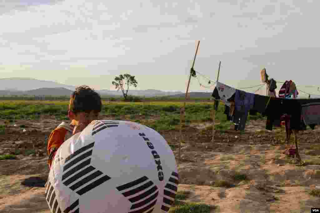 A child inflates a large football. NGOs and volunteers have stepped in to offer assistance, with a cultural centre among the many makeshift facilities built to help entertain the camps' youngsters. (J. Owens/VOA)