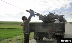 FILE - A Free Syrian Army fighter cleans an anti-aircraft artillery gun near the Menagh military airport in Aleppo's countryside, Feb. 17, 2013.