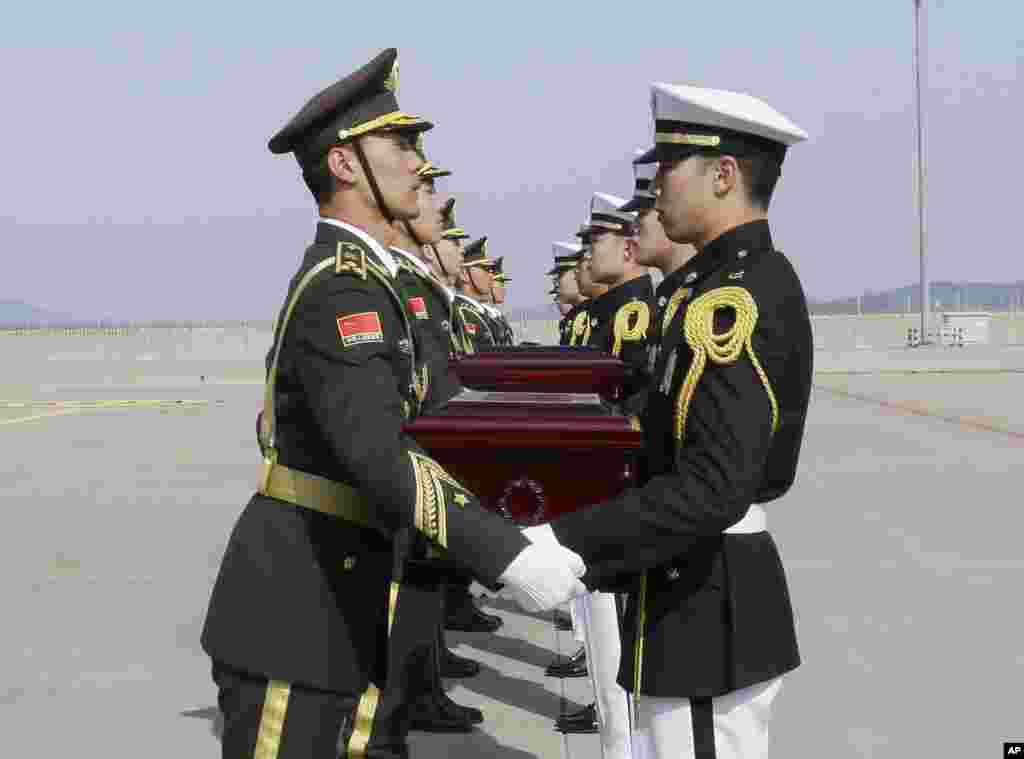 Chinese honor guards, left, receive caskets containing the remains of Chinese soldiers from South Korean honor guards during the handing over ceremony at the Incheon International Airport in Incheon, South Korea. The remains of 28 Chinese soldiers killed during the 1950-53 Korean War were returned home for permanent burial.