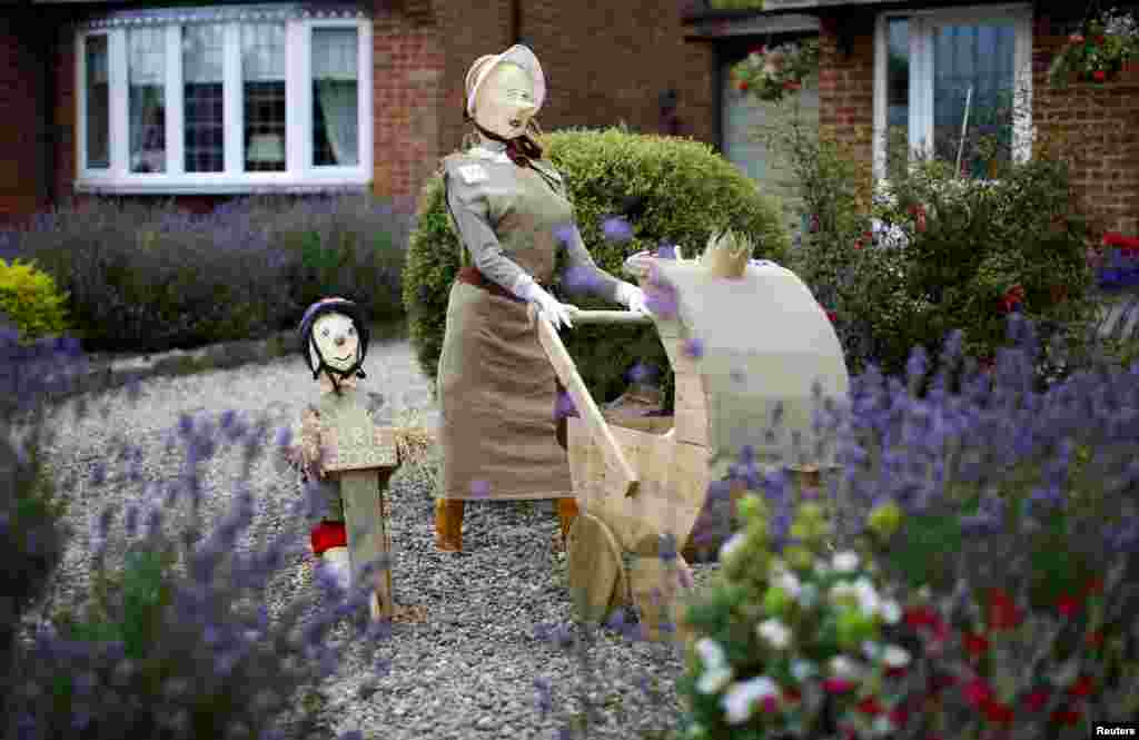A scarecrow of Britain&#39;s Prince George and Princess Charlotte with their nanny stands in a garden during the Scarecrow Festival in Heather, Britain.