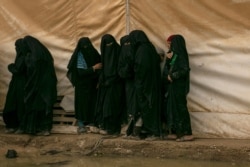 FILE - Women line up for aid supplies at Al-Hol camp, home to Islamic State-affiliated families near Hasakeh, Syria, March 31, 2019.