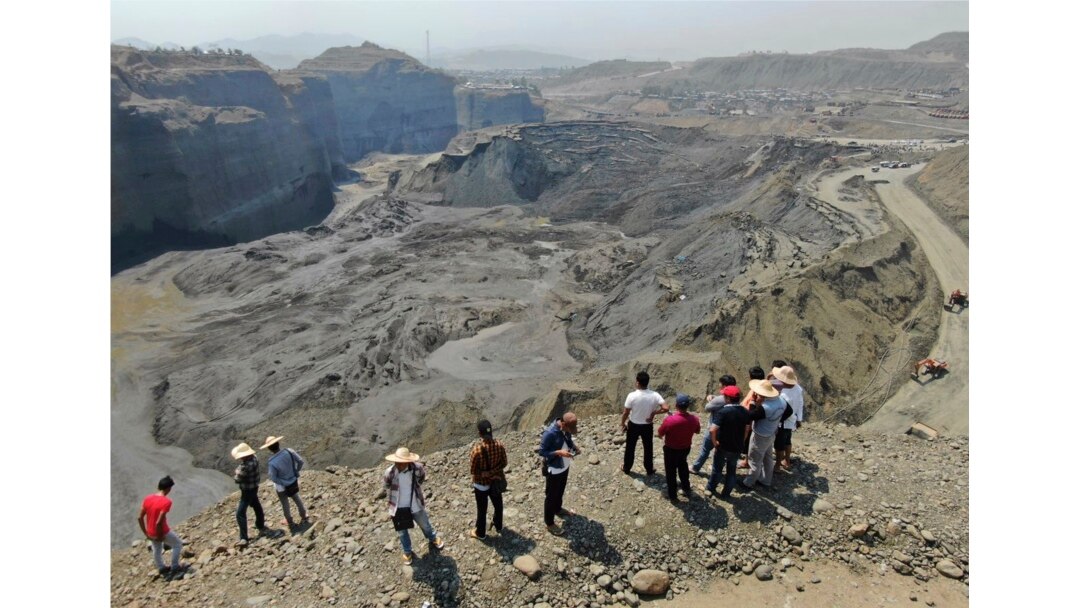 People stand atop a ridge overlooking the scene of a mudslide at a jade gemstone mining site, April 23, 2019, in Hpakant area of Kachin state, northern Myanmar.