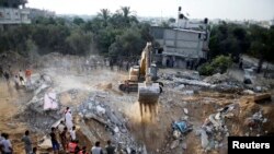 Warga Palestina berkumpul saat buldoser mencari para korban di antara reruntuhan bangunan di Khan Younis di selatan Jalur Gaza (21/7). (Reuters/Ibraheem Abu Mustafa)