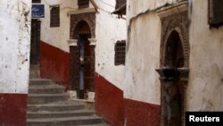 A boy waves as he stands behind the door of a Moorish house in the old city of Algiers Al Casbah, Algeria, Dec. 9, 2015. 