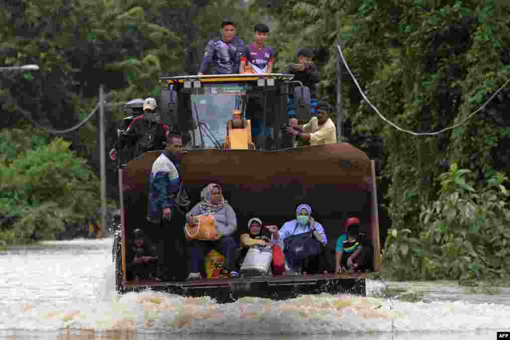 Residents ride a digger vehicle through floodwaters following heavy monsoon downpour in Lanchang, Malaysia's Pahang state.