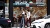 FILE - A couple walks past a Persian pizza restaurant near Persian Square in Westwood, Los Angeles.