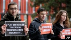 FILE - Protesters hold banners outside the building where Jeremy Corbyn, Leader of Britain's opposition Labor Party, attended the launch of Labor's General Election manifesto, at Birmingham City University, England, Nov. 21, 2019. 