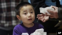 A young boy carries his allotment of food at a shelter after being evacuated from areas around the damaged Fukushima nuclear power plant in Japan, March 20, 2011.