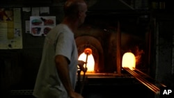 A glass-worker heats glass in a methane powered ovens in a factory in Murano island, Venice, Italy, Oct. 7, 2021.