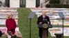 President Joe Biden speaks as first lady Jill Biden listens on the South Lawn of the White House during a ceremony to mark World AIDS Day with survivors, their families and advocates, in Washington, Dec. 1, 2024.