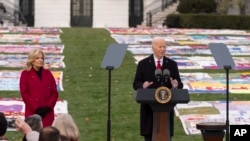 President Joe Biden speaks as first lady Jill Biden listens on the South Lawn of the White House during a ceremony to mark World AIDS Day with survivors, their families and advocates, in Washington, Dec. 1, 2024.