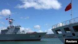 The Chinese People's Liberation Army (PLA) Navy replenishment ship Qiandaohu (866) (L) sails past the PLA Navy hospital ship, Peace Ark, as it docks at the Joint Base Pearl Harbor Hickam to participate in the multi-national military exercise RIMPAC 2014, 