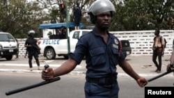 Des policiers montent la garde alors que des manifestants défilent à Accra, la capitale du Ghana, contre l'expansion de sa coopération en matière de défense avec les États-Unis, Ghana, le 28 mars 2018.