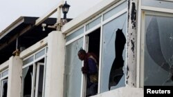 সোমালিয়ার মোগাদিসুতে লিডো সৈকতে আল-শাবাব জঙ্গিদের হামলার পরে একজন সোমালি পুলিশ ভাঙা জানালা দিয়ে দেখছেন। ১০ জুন, ২০২৩। ফাইল ছবি।