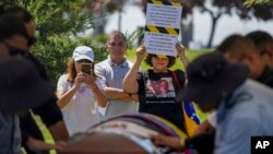 Un asistente sostiene un cartel de protesta durante el entierro del ex militar venezolano Roland Ojeda en el cementerio de Canaán en Santiago, Chile, el viernes 8 de marzo de 2024. (Foto AP/Esteban Félix)