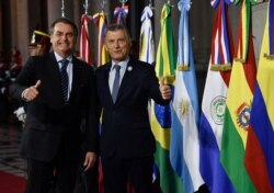FILE - Argentina's President Mauricio Macri, right, gives a thumbs up to photographers with Brazil's President Jair Bolsonaro during the Mercosur Summit in Santa Fe, Argentina, July 17, 2019.