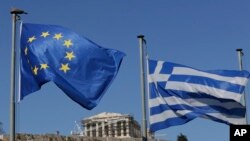 La bandera griega (derecha) y la bandera de la Unión Europea ondean sobre la colina de la Acrópolis en Atenas, el domingo, 5 de julio de 2015.