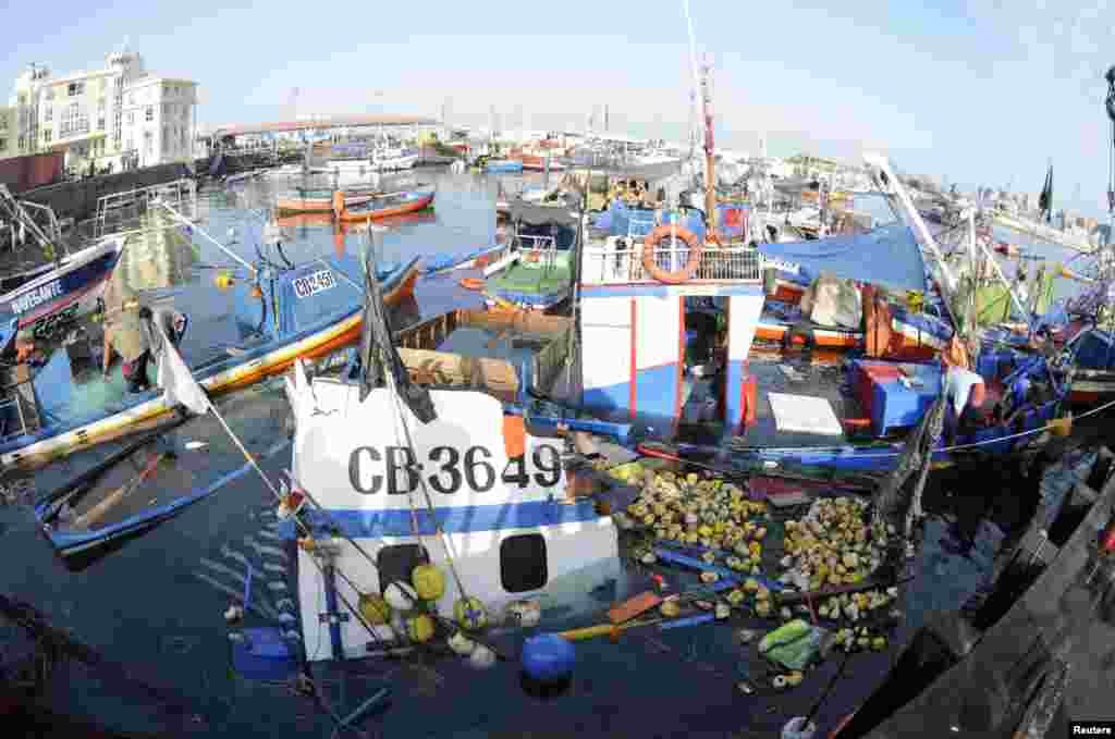 Fishermen inspect boats sunk after a small tsunami hit the northern port of Iquique, Chile, April 2, 2014. 