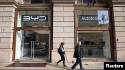 FILE - People walk in front of a store opened by Chinese electric car maker BYD in Milan, Italy, on March 20, 2024.