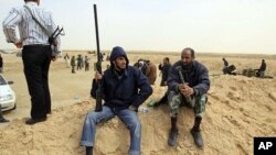 A rebel holds a gun on the outskirts of Ajdabiya, on the road leading to Brega, Libya, March 2, 2011