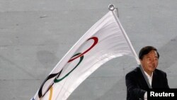 Walikota Nanjing, Ji Jianye, melambaikan bendera olimpiade, sesaat setelah menerimanya dari Presiden Komite Olahraga Internasional (IOC), Jacques Rogge (tidak nampak dalam foto), dalam upacara penutupan Olimpiade pemuda (YOG) di Singapura, 26 Agustus 2010 (Foto: dok). 