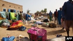 People who survived after the sinking of a river boat walk near their belongings on the banks of the Niger river, Oct. 13, 2013 in Koubi.