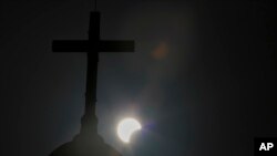 FILE—A partial solar eclipse is seen behind a cross on the steeple of the St. George church, in downtown Beirut, Lebanon, Sunday, June 21, 2020.