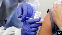 FILE - A man receives a shot in the first-stage safety study clinical trial of a potential vaccine for COVID-19, the disease caused by the new coronavirus, at the Kaiser Permanente Washington Health Research Institute in Seattle, March 16, 2020..