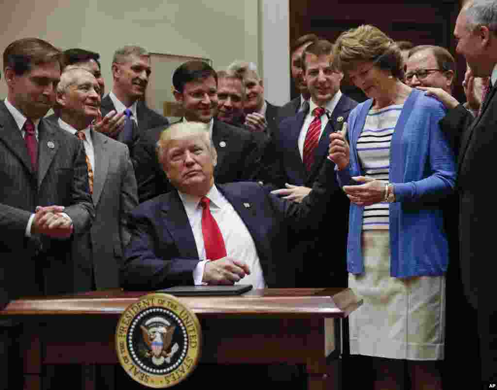 Donald Trump, entrega a caneta que usou para assinar o decreto lei à senadora Lisa Murkowski, na sala Roosevelt na Casa Branca. Abril &nbsp;28, 2017.&nbsp;