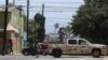 Fuerzas de seguridad patrullan una calle de Tijuana, México, donde algunos vehículos fueron incendiados por presuntos delincuentes el viernes 12 de agosto de 2022. Foto Reuters.