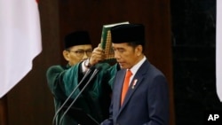 Indonesian President Joko Widodo, right, reads his oath during his inauguration ceremony at the parliament building in Jakarta, Oct. 20, 2019. 