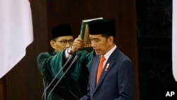 Presiden Indonesia Joko Widodo membacakan sumpahnya saat upacara pelantikannya di gedung parlemen di Jakarta, 20 Oktober 2019. (Foto: AP)