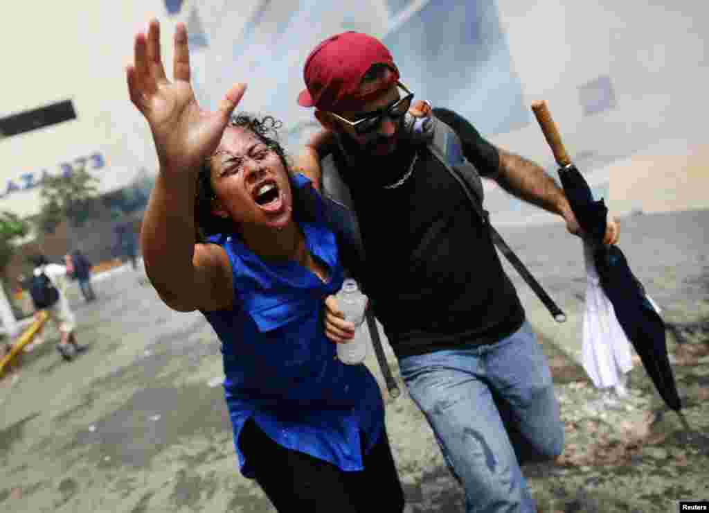 A woman affected by tear gas is helped during a May Day protest against austerity measures, in San Juan, Puerto Rico, May 1, 2018.