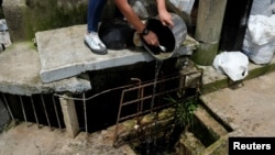 Un trabajador de salud vacía un recipiente con agua estancada para prevenir la reproducción de mosquitos Aedes aegypti y mitigar un brote de dengue en la Ciudad de Guatemala, Guatemala, 23 de julio de 2024. 