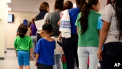 ARCHIVO - En esta fotografía del jueves 9 de agosto de 2018 proporcionada por el Servicio de Inmigración y Control de Aduanas de Estados Unidos, madres y sus hijos hacen fila en el Centro Residencial Familiar del Sur de Texas en Dilley, Texas.