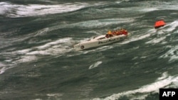 FILE - The injured crew of demasted Australian yacht "Stand Aside" await rescue by helicopter as they tow a life-raft in Bass Strait during the Sydney-to-Hobart ocean race, Dec. 27, 1998.