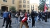 A Lebanese demonstrator hurls rocks over a fortified gate, leading to the Lebanese Parliament building, in downtown Beirut, March 13, 2021, during a protest against the political system.