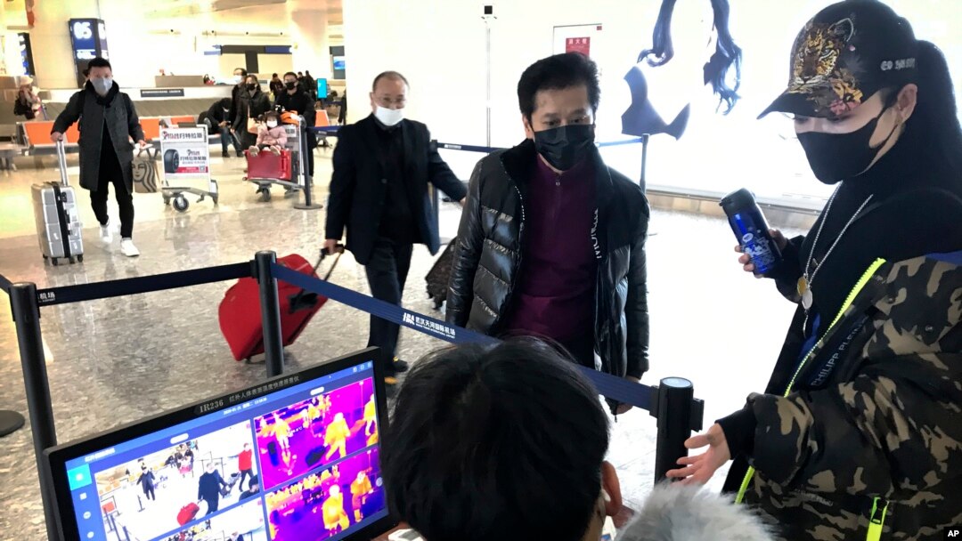 Travelers pass through a health screening checkpoint at Wuhan Tianhe International Airport in Wuhan in southern China's Hubei province, Tuesday, Jan. 21, 2020. A fourth person has died in an outbreak of a new coronavirus in China, authorities said…